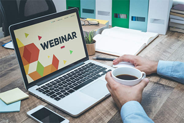 Man drinking coffee and attending webinar on laptop.