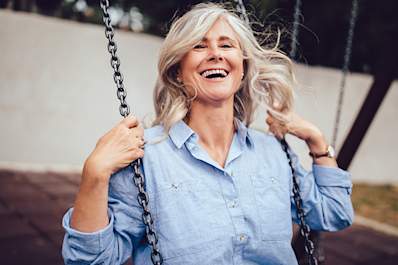 Middle age woman having fun on a swing set.