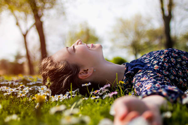 blissful young woman lying in the grass image