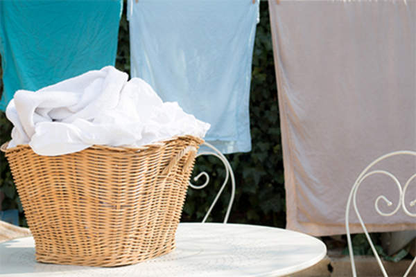 Laundry basket and sheets hung on clothes line.