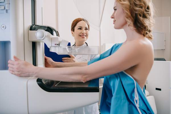 Smiling radiologist standing near patient while making mammography diagnostics