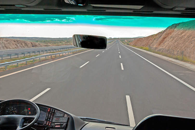 Windshield of a bus looking out on the highway.