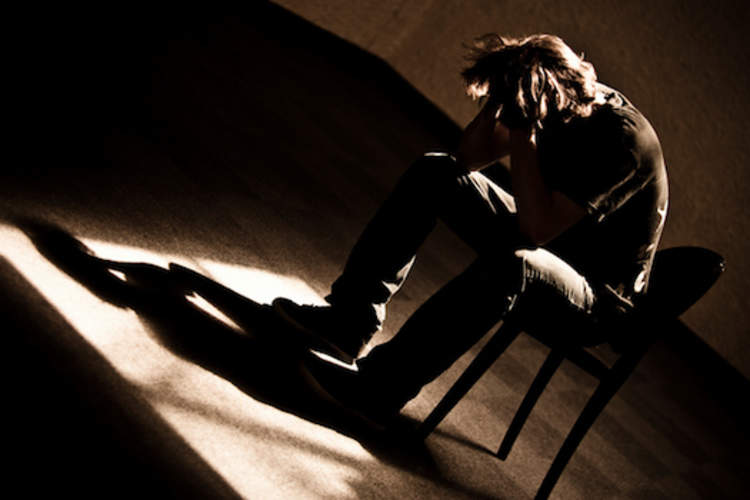 Depressed man sitting in dark room.