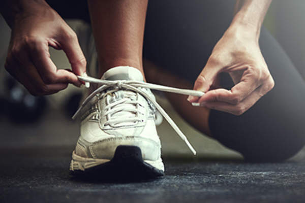 Person tying shoelaces on sneakers.