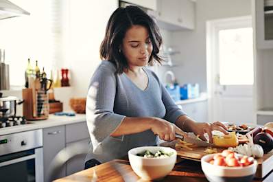 Woman cooking a nutritious meal to protect her health.