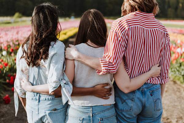 three young women with arms wrapped around each other