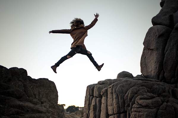 person jumping between rocks