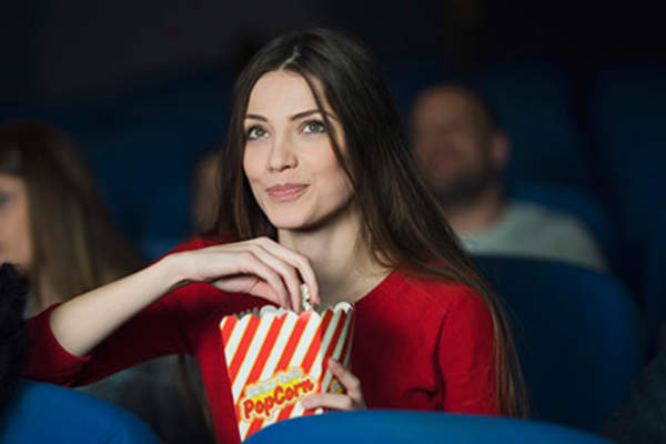 Woman at the movies eating popcorn.