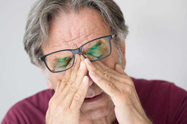 Senior man fatigued and rubbing his eyes.