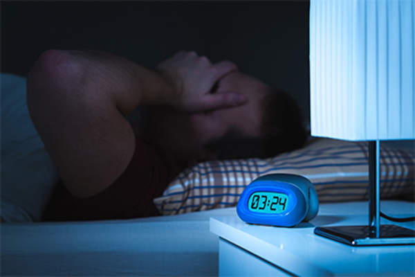 Man having trouble sleeping in bed.