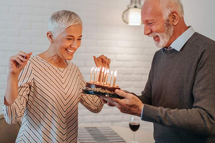Senior couple celebrating special occasion with cake and candles.