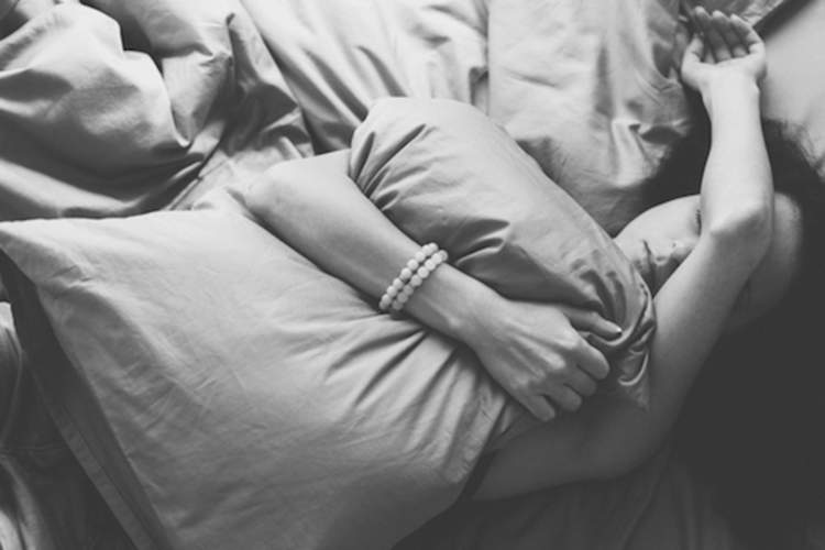 Woman clutching pillow on bed.