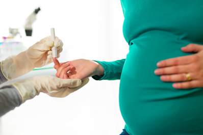 Pregnant woman having blood sugar tested at doctors office.