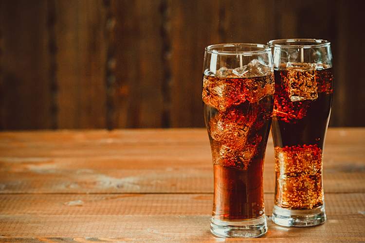 Two ice cold glasses of soda on wood table.