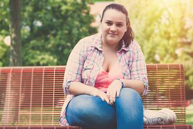 Pretty, overweight teen girl sitting on park bench.