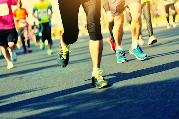 Marathon athletes legs running on city road