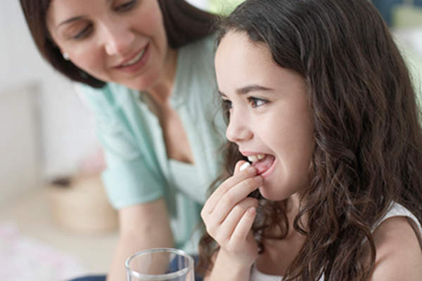 Child taking a pill.