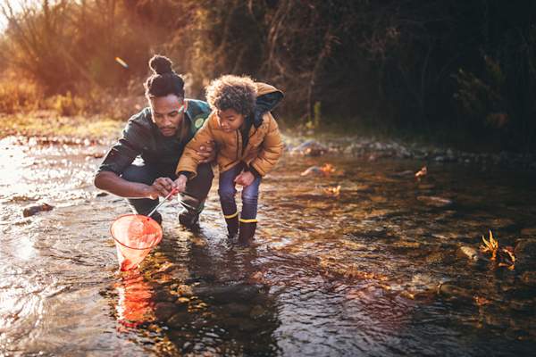 Father helping son catch small fish.