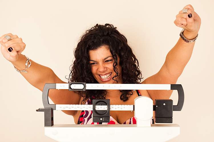 Woman celebrating weight loss on a scale.