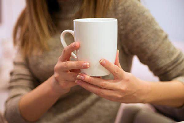Woman holding white cup of coffee or tea