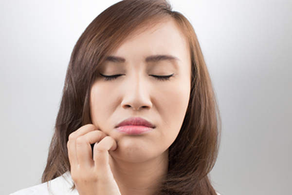 Young woman scratching an itch on her face.