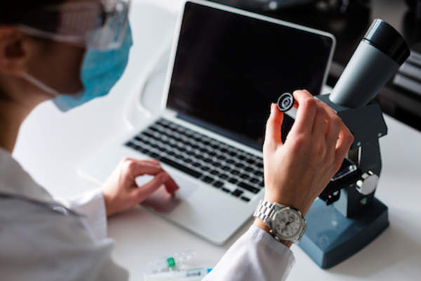 Research concept scientist with microscope and computer.