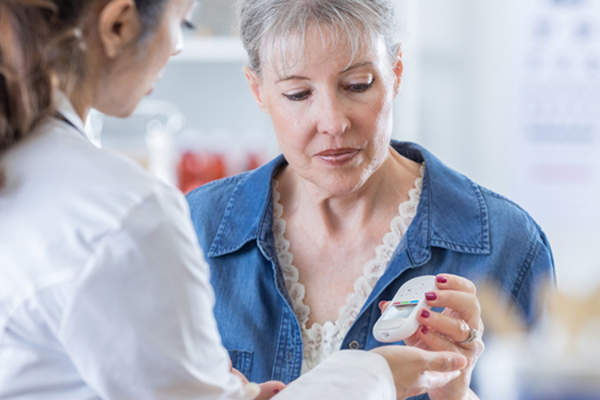 Woman and doctor looking at blood glucose meter.
