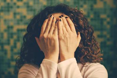 Embarrassed woman hiding her face with her hands.