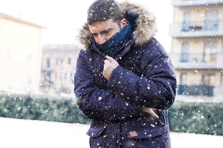 Man bundled up outside in snowstorm.