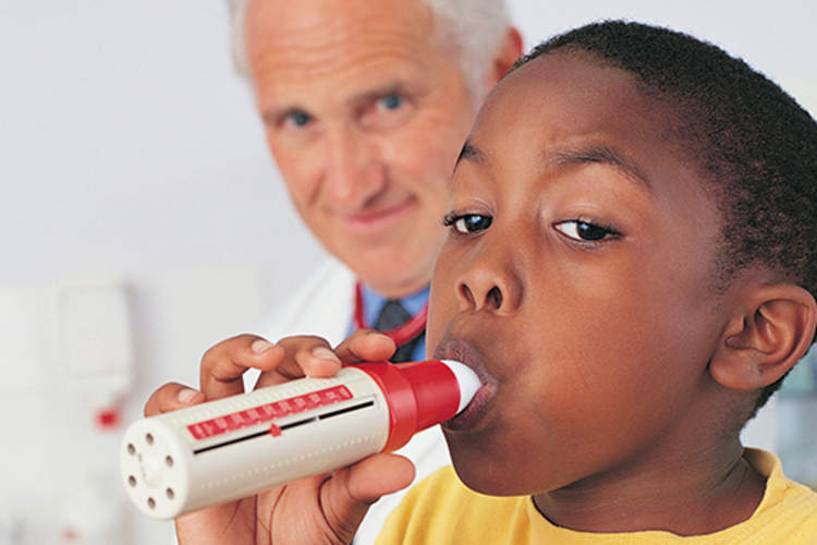 boy using a spirometer as part of a pulmonary function test