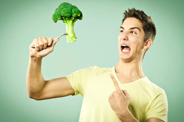 Unhappy boy with a broccoli