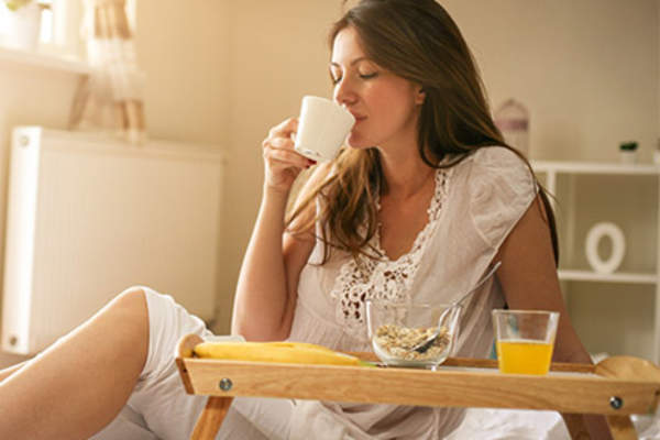 Young woman having breakfast in bed.