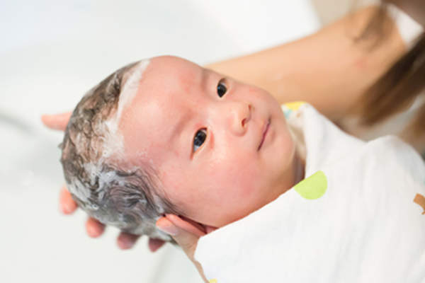 Mom washing baby's hair in the bath.