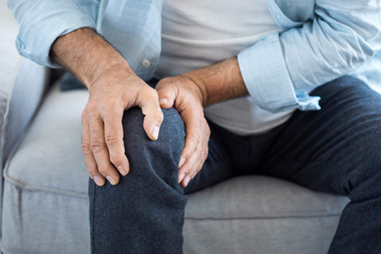 Man with knee pain holding his knee.