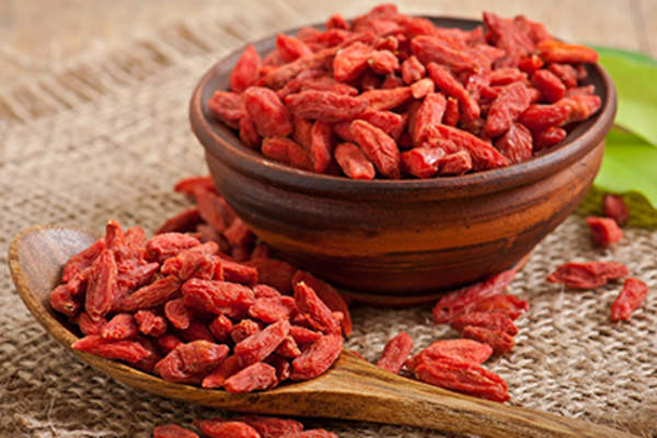 Red dried goji berries in wooden spoon