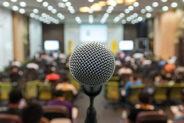 Microphone in front of podium with a crowd in the background.