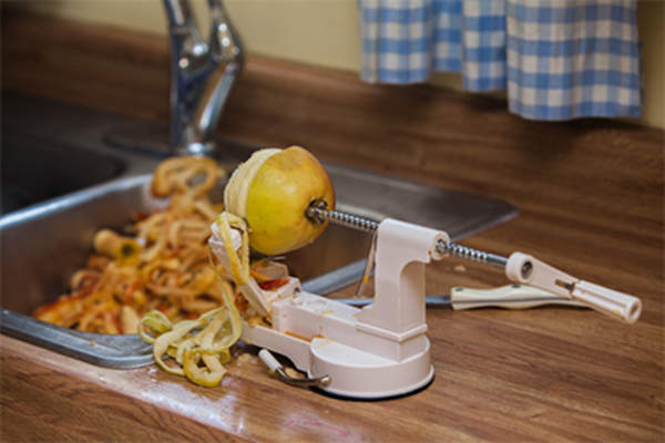 Apple peeler, corer, slicer on kitchen counter peeling an apple.