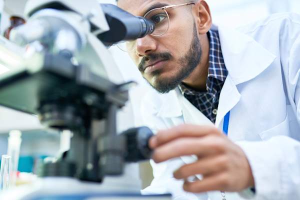 Scientist using microscope for medical research.