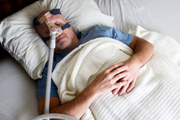 Man sleeping in bed using a CPAP.