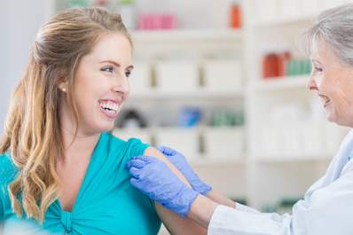 Happy young woman getting a flu shot in a pharmacy.