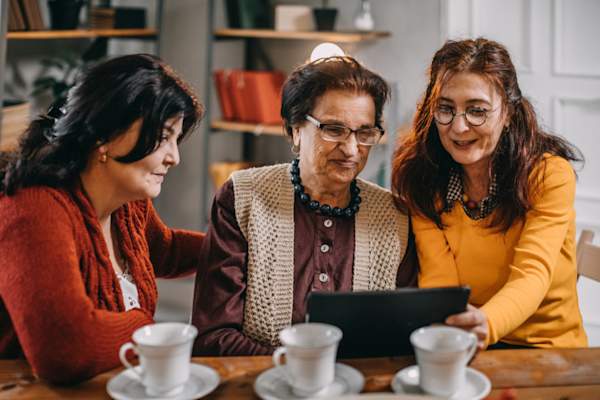 three senior women, family, looking at tablet
