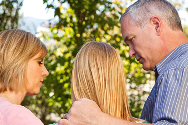 parents with sad teen girl image