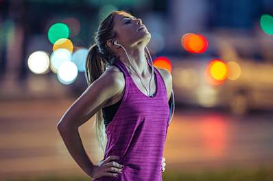 Tired young woman out for a run at night.