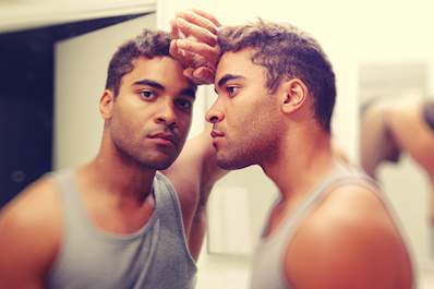Depressed man leaning into his reflection.