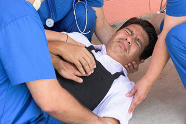 Health care providers helping man having seizure.