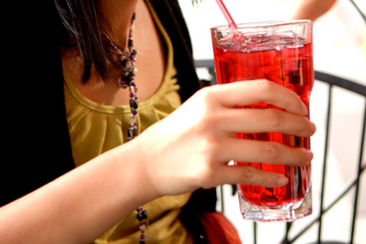 Young woman drinking a glass of cranberry juice.