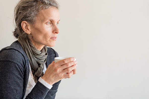 Adult woman thinking holding cup of tea.