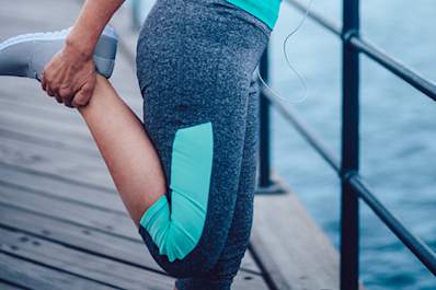 Woman stretching leg on boardwalk before running.
