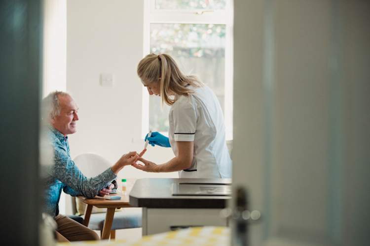 doctor with diabetes patient testing blood sugar