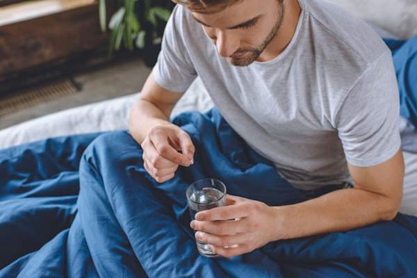 man in bed taking pill
